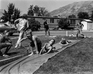 Kids playing slip-and-slide in a trailer park.