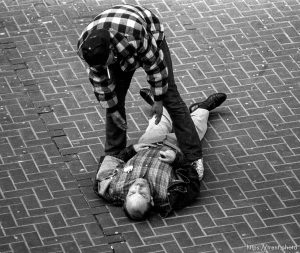 Man on ground being offered assistance at 5th and Market St.