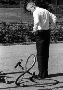Man looking at crunched bike at auto vs. bicycle crash.