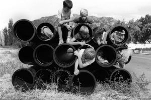 Kids playing on stack of pipes.