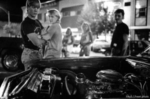 Kids checking out car's engine on Center Street at night.
