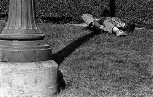 Man sleeping in shade of post.