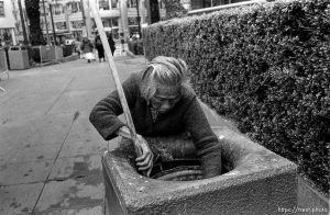 Woman picks through trash can