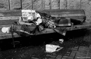 Homeless woman sleeping on bench with 