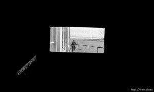 Woman takes a photo and Bay Bridge through tiny window at Alcatraz