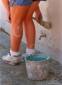 Girl painting with smiley face on her calf.