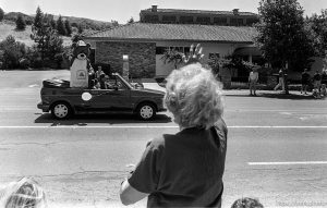 Lady waving to bear in parade.