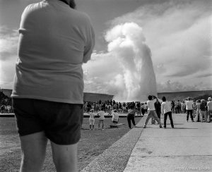 Man photographing Old Faithful geyser at the Old Faithful Lodge.