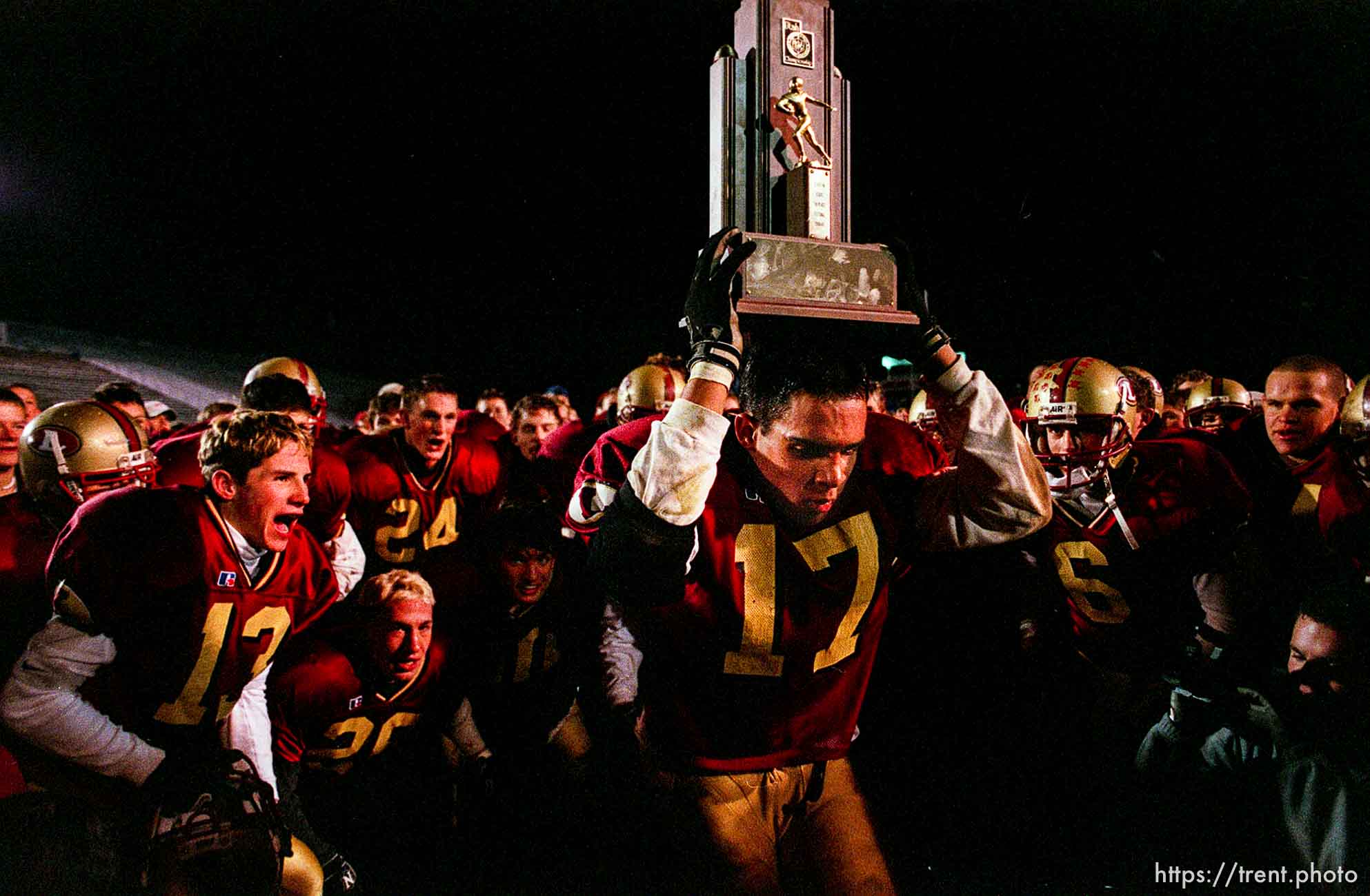 Logan's Ryan Bohm leads his teammates in a song while holding the 4A championship trophy as Logan defeats Highland in the 4A state football championship game Friday night in Ogden. photo by Trent Nelson. 11/17/2000