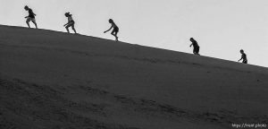 Children climb a large sand hill north of Moab. The sight is a long time local attraction, where kids climb up to the top and get down in a variety of ways: jumping, sprinting, or sliding on cardboard scraps.
Photo by Trent Nelson, 07.09.2003, 8:34:01 PM