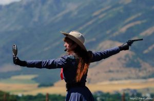 Famous western sharpshooter Annie Oakley (Marna Jean) uses a mirror to take aim at a balloon in her partner Frank Butler (Doug Davis)'s mouth during a Wild West Show that kicked off the Festival of the American West at Wellsville's American West Heritage Center.
