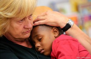children taking naps in volunteers' arms in day care center at Camp Williams, where people who were evacuated from the hurricane Katrina disaster in New Orleans, are making a go of it.