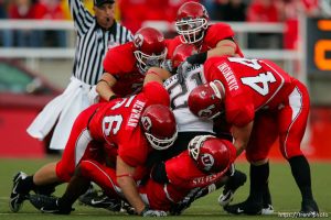 Salt Lake City - A group of Utah defenders including Greg Newman (left), Stevenson Sylvester (bottom) and Joe Jiannoni (right)  bring down San Diego State running back Atiyyah Henderson. Utah vs San Diego State (SDSU) college football at Rice-Eccles Stadium.