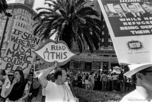 Protest signs including middle finger at Act-Up protest during visit of President Bush