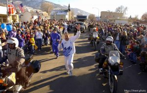 The Olympic Torch Relay arrives on Main Street in Manti Tuesday afternoon. Torchbearer Leonard Moon runs brimming with excitement, and then gives his wife Delores a back-bending kiss as she takes her turn as the next torchbearer in the schedule. 02.05.2002, 3:54:27 PM