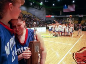 North Sevier basketball players Ann Braithwaite and Shadoe Shaheen (right) hold the second place trophy and grieve while the state champion Beaver Beavers celebrate their victory.