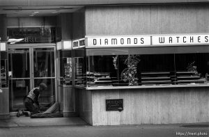 Homeless man making his bed in a jewelry store doorway.