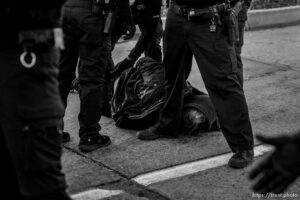 (Trent Nelson  |  The Salt Lake Tribune) Salt Lake City police officers working the cleanup of a series of campsites in Salt Lake City on Wednesday, Dec. 9, 2020. An activist is arrested after a group stood in front of a police car, not allowing it to pass.