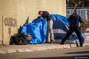 (Trent Nelson  |  The Salt Lake Tribune) Police officers talk to a man living in a tent just off State Street in Salt Lake City on Monday, Dec. 19, 2022.