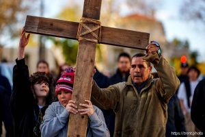 (Trent Nelson  |  The Salt Lake Tribune) Jr Salazar carries the cross with an assist from Josiah Salazar, left, and John Salazar, right, in the annual Good Friday procession in Salt Lake City on Friday, April 18, 2025.